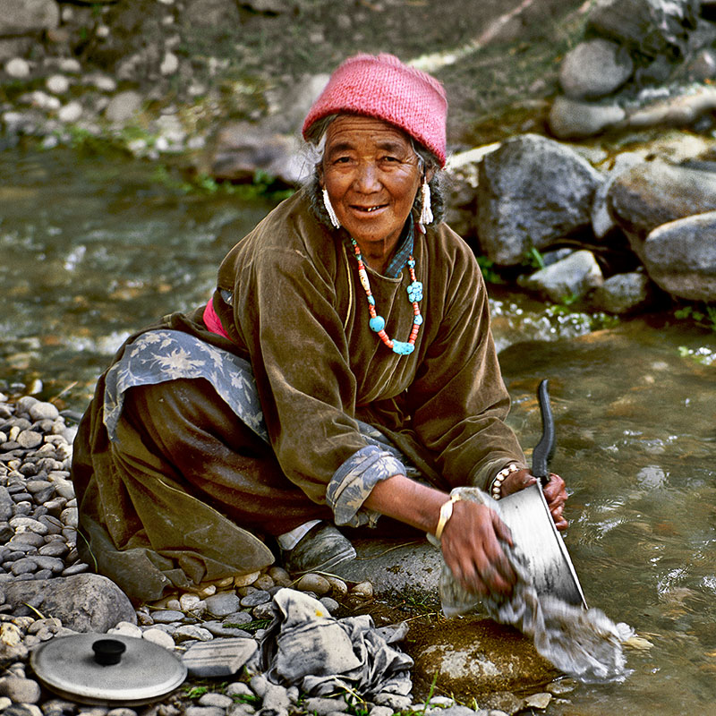 Femme lavant la vaisselle à la rivière - Ladakh (Inde)